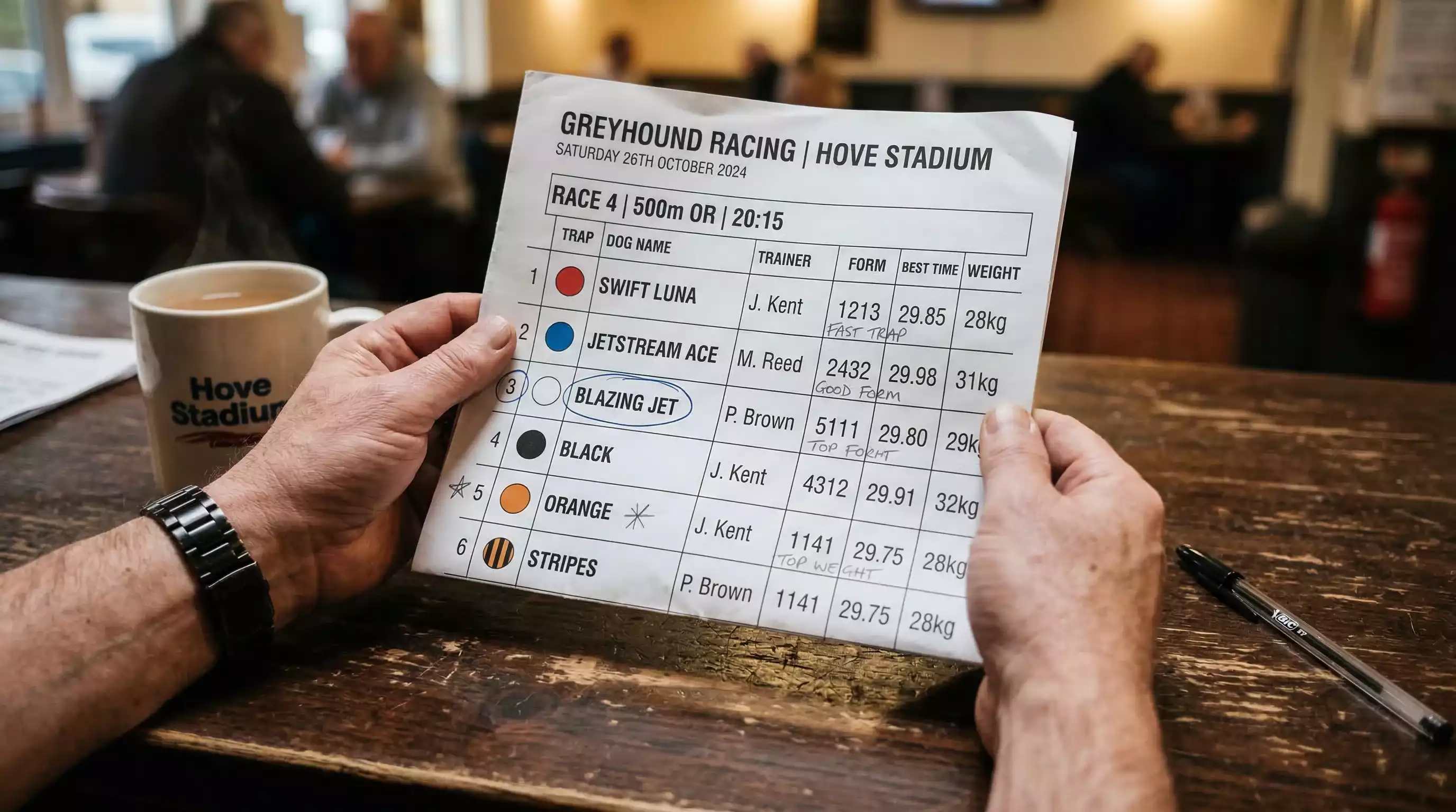 Person studying a greyhound racecard with form data and abbreviations printed on paper under warm light